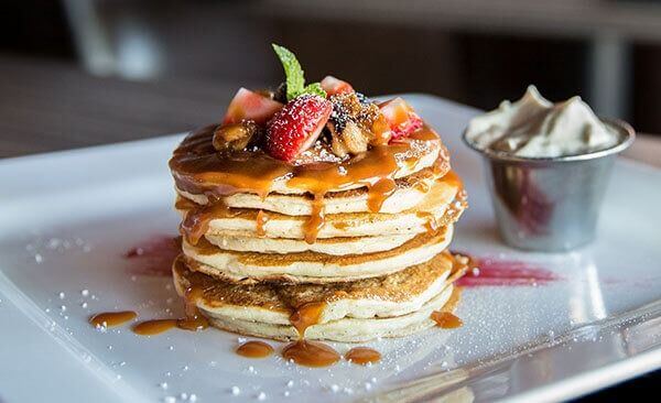 Stack of strawberry pancakes with powdered sugar